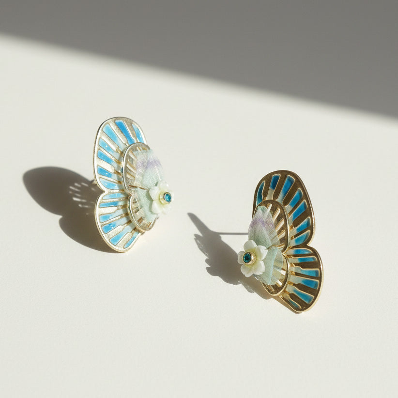Pair of earrings with blue and gold design on a light background