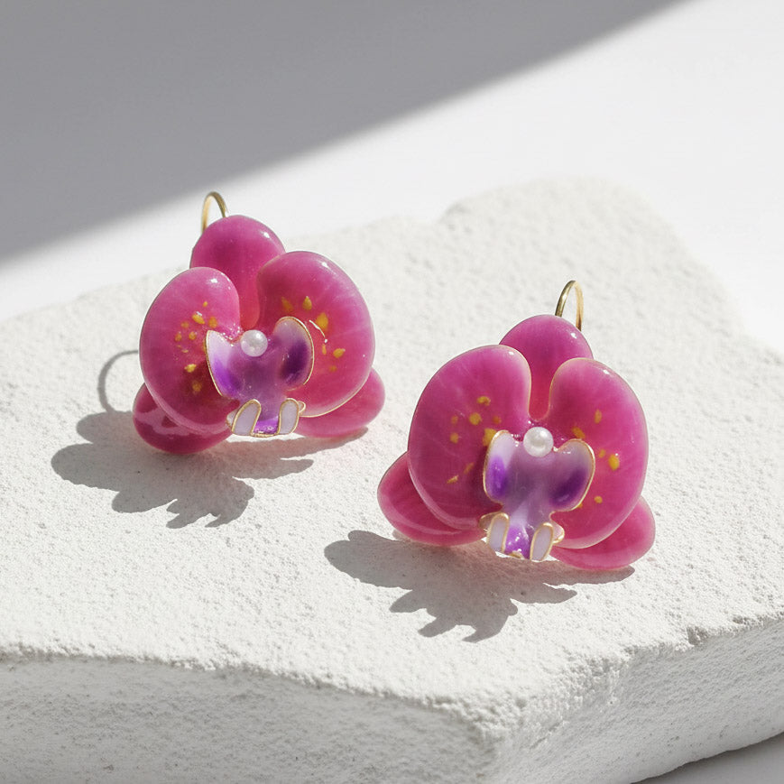 Pink and purple orchid flower earrings with pearl accents, handcrafted resin floral jewelry on light background.