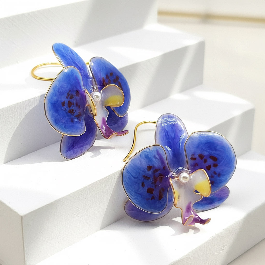Blue orchid-shaped earrings on a white geometric background