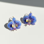 Blue orchid-shaped earrings on a light background