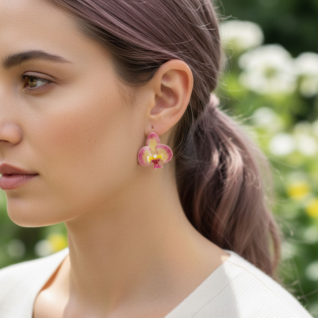 Woman wearing pink orchid earrings with a blurred natural background