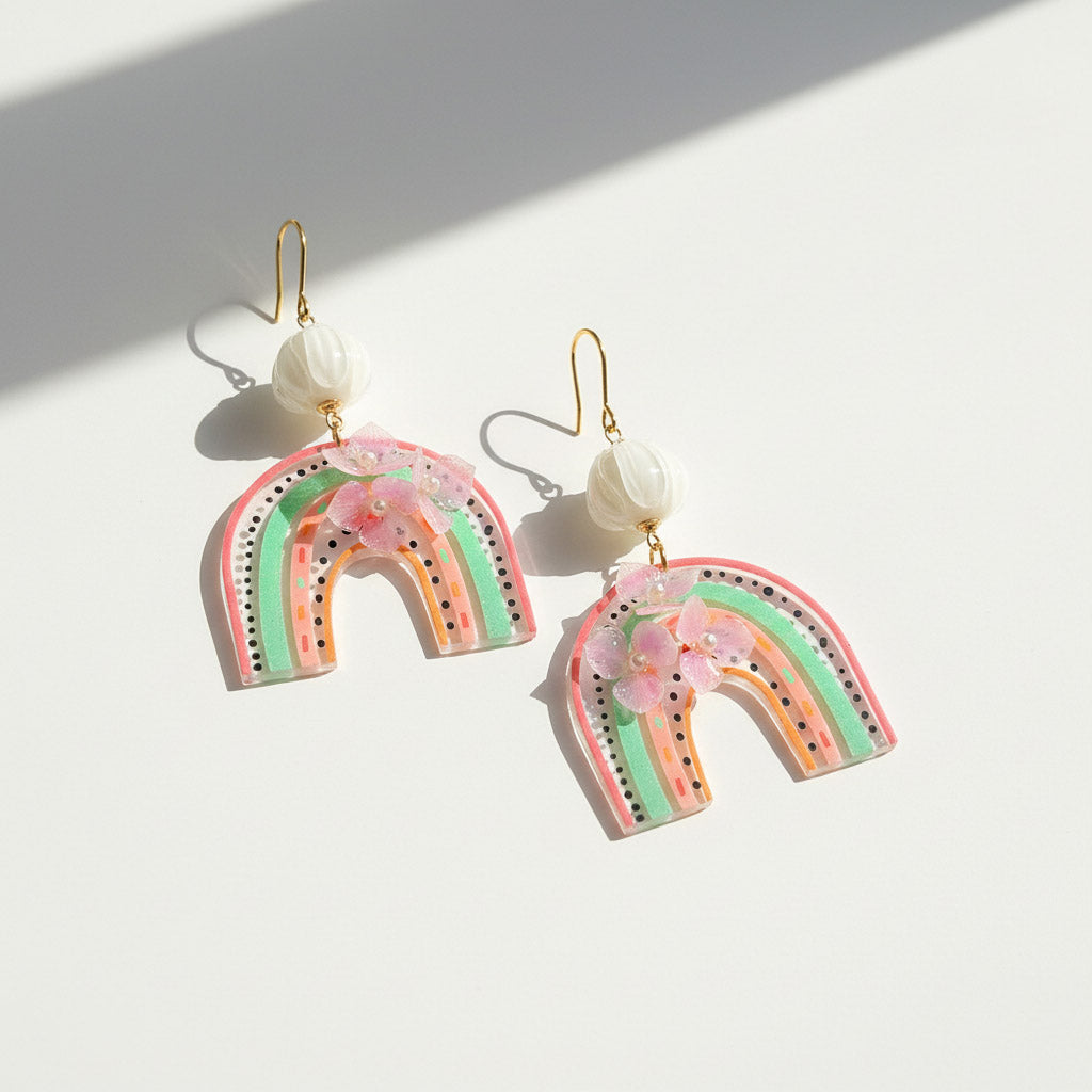 Rainbow-shaped earrings with floral details on a white background