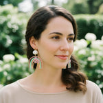 Woman wearing colorful earrings with a blurred green background