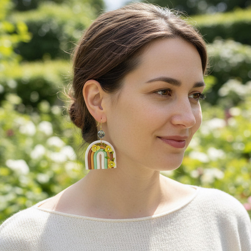 Woman wearing rainbow polymer clay statement earrings with yellow hydrangea flowers