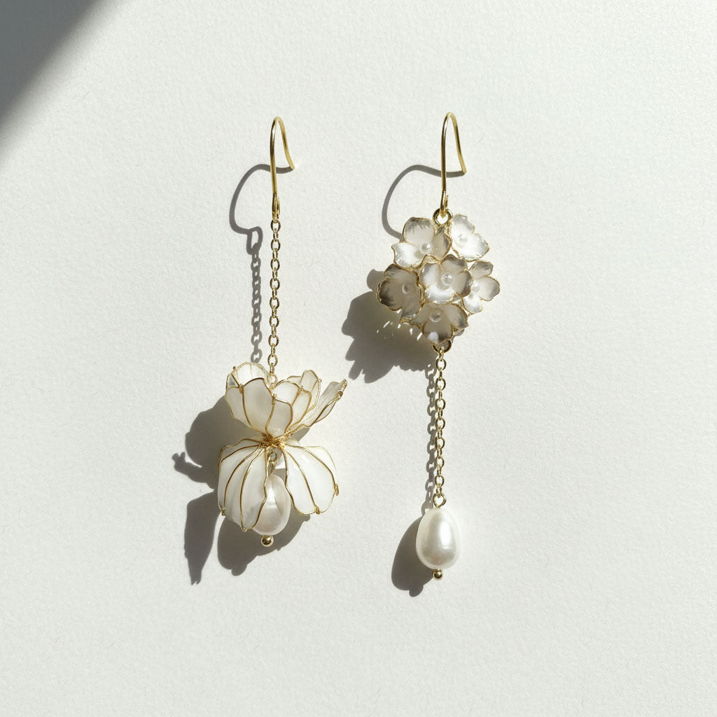 Pair of delicate earrings with floral designs and pearl-like beads on a light background