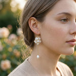Close-up of a woman wearing pearl earrings with a blurred natural background