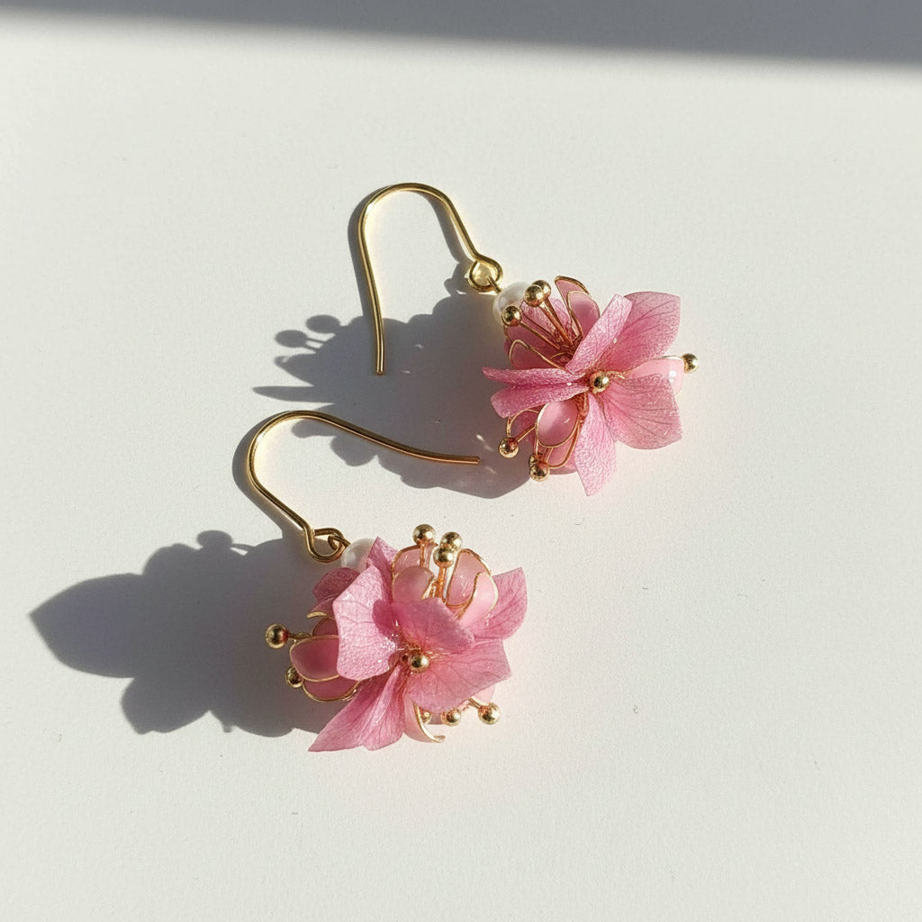 Pair of pink floral earrings with gold hooks on a white background