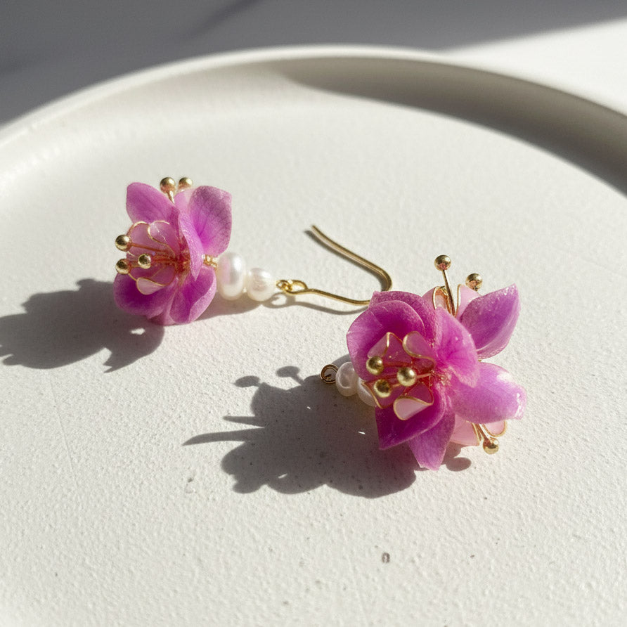 Pink floral earrings with gold accents on a white surface
