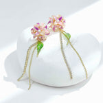 Pair of floral earrings with pink and gold accents on a white stone surface