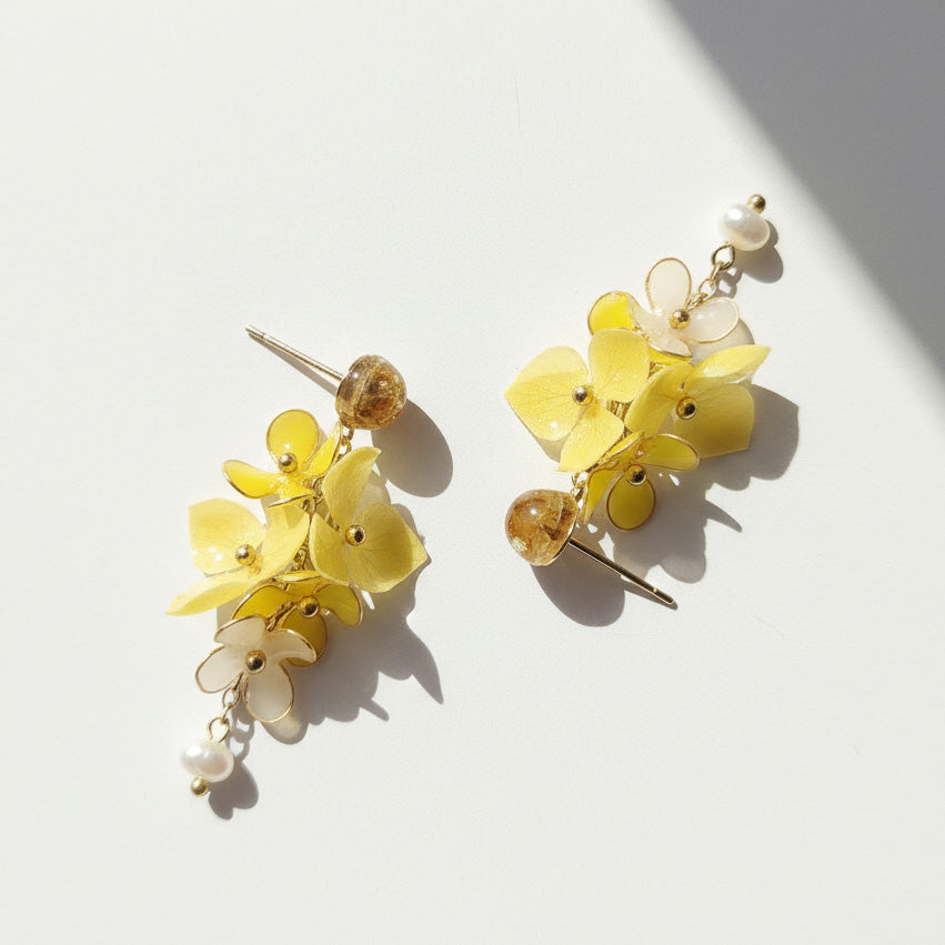 Yellow floral earrings with pearl accents on a light background