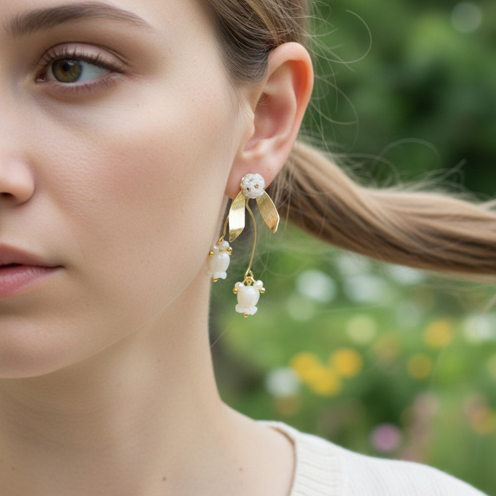 Close-up of a woman wearing gold earrings with white stones against a blurred natural background