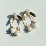 Gold and pearl earrings on a light gray background