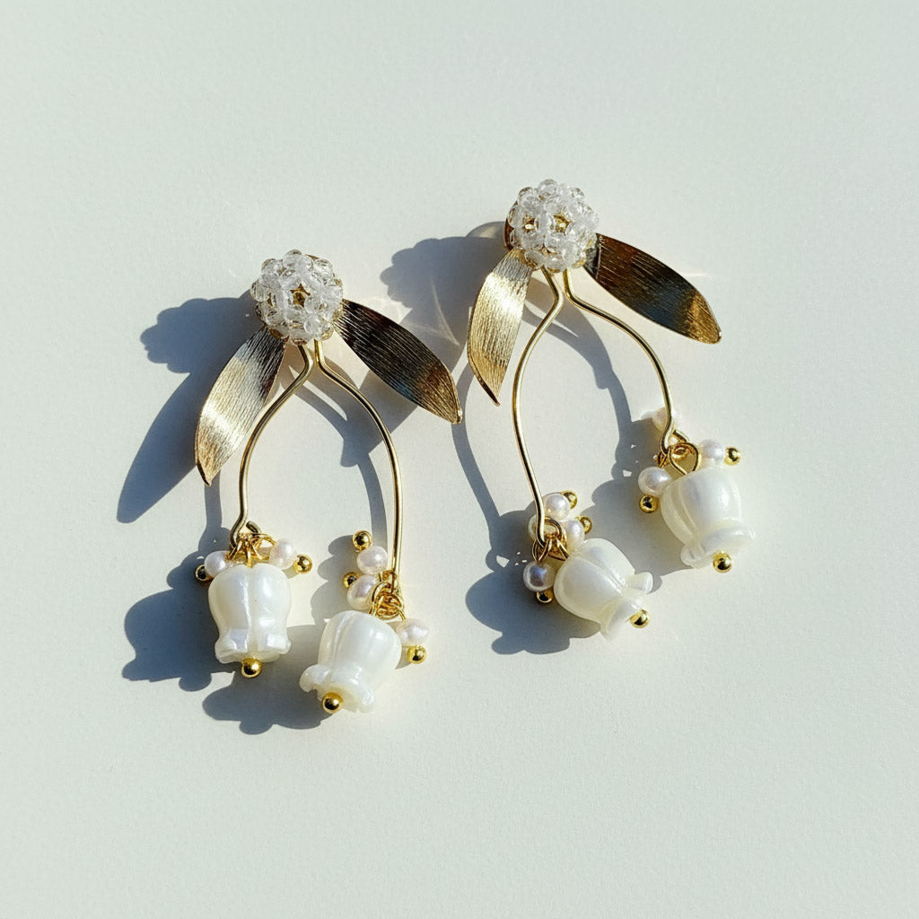 Gold and pearl earrings on a light gray background