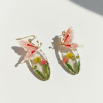 Butterfly-shaped earrings with floral details on a white background