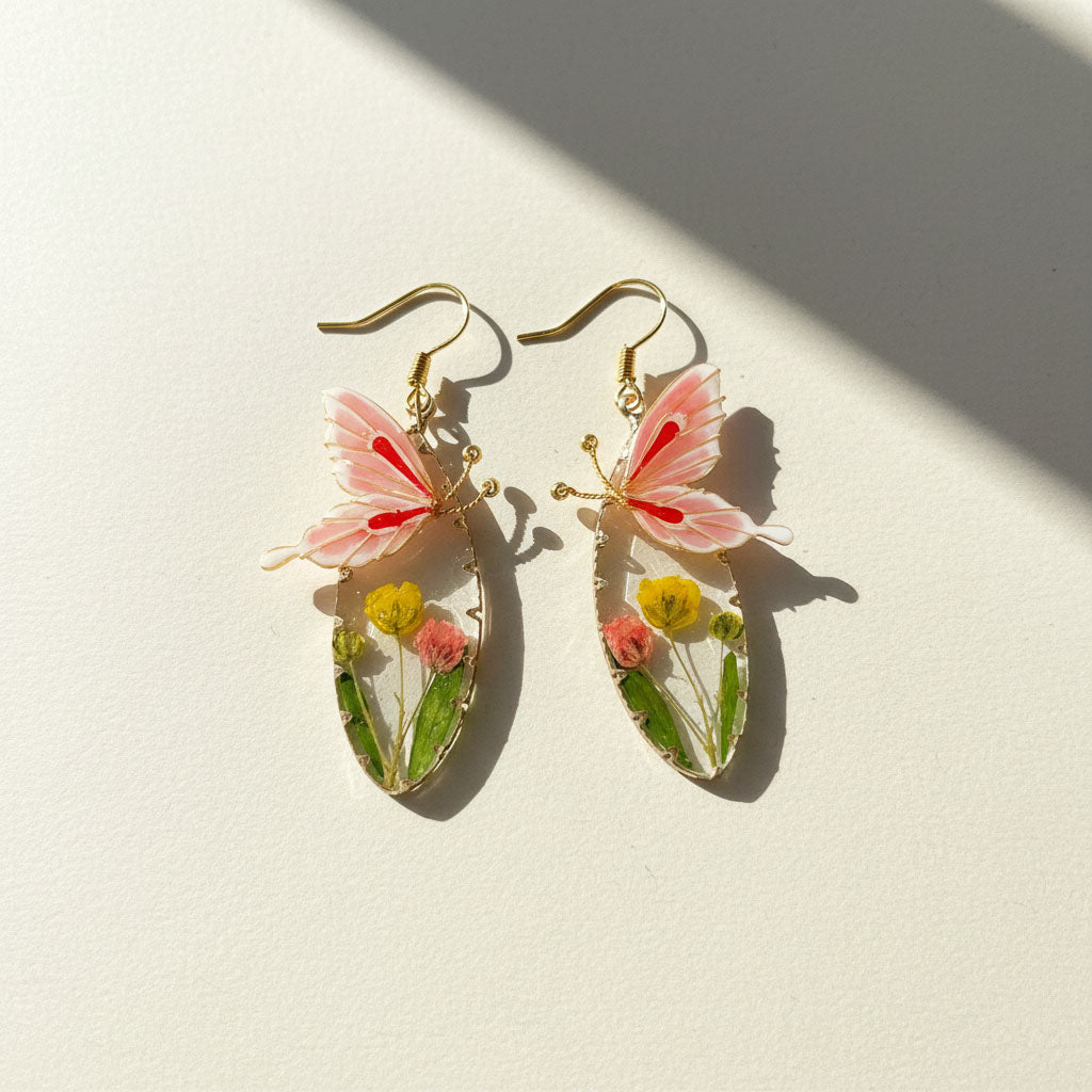 Butterfly-shaped earrings with floral elements on a light background