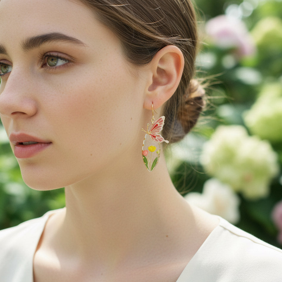 Woman wearing butterfly earrings with a blurred floral background