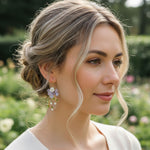 Model wearing lavender petal and pearl vine earrings in sunlight garden setting.