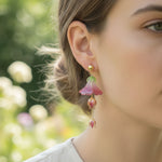 Close-up of a person wearing floral earrings with a blurred natural background