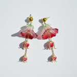 Pair of pink flower-shaped earrings with gold accents on a light gray background