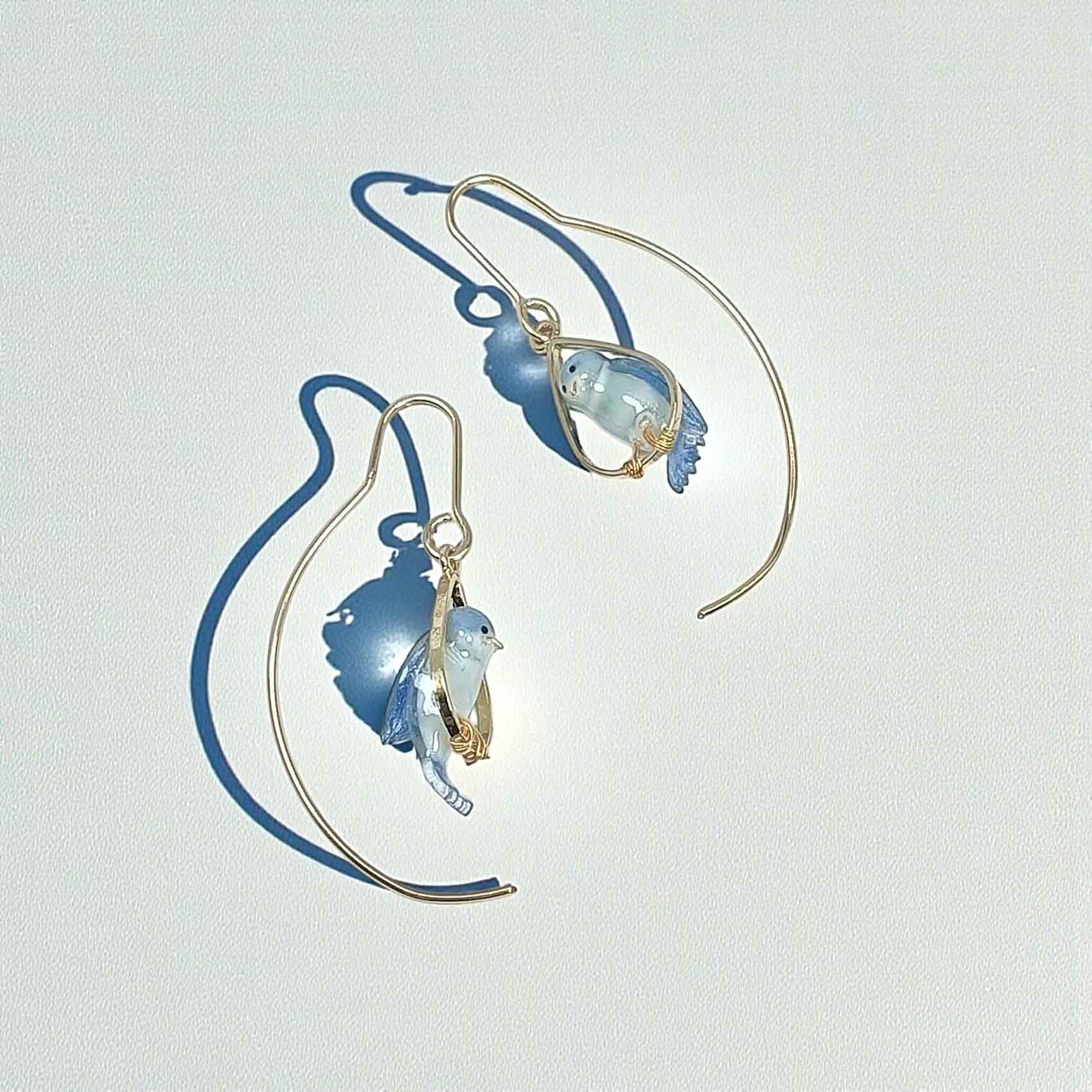 Pair of gold and blue earrings on a light gray background