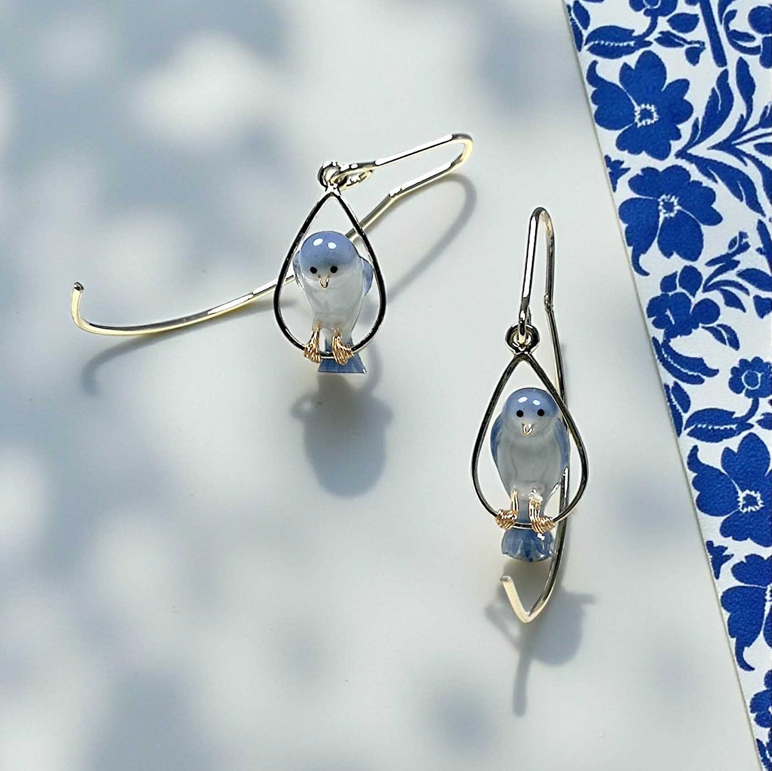Pair of earrings with bird design on a floral-patterned background