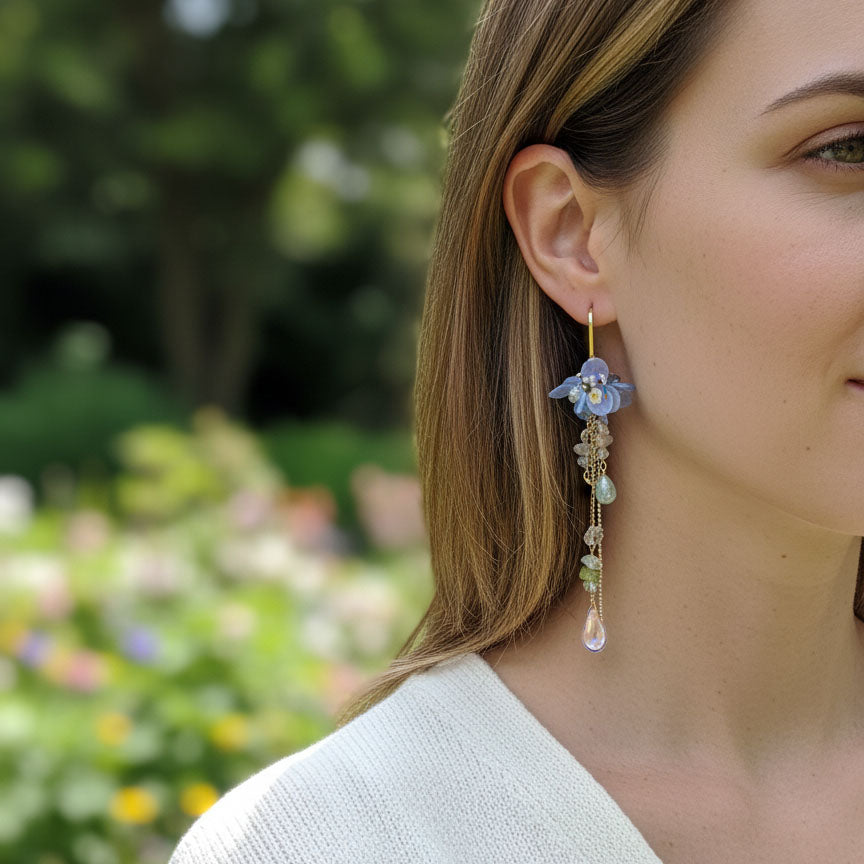Close-up of a woman wearing floral earrings with a blurred garden background