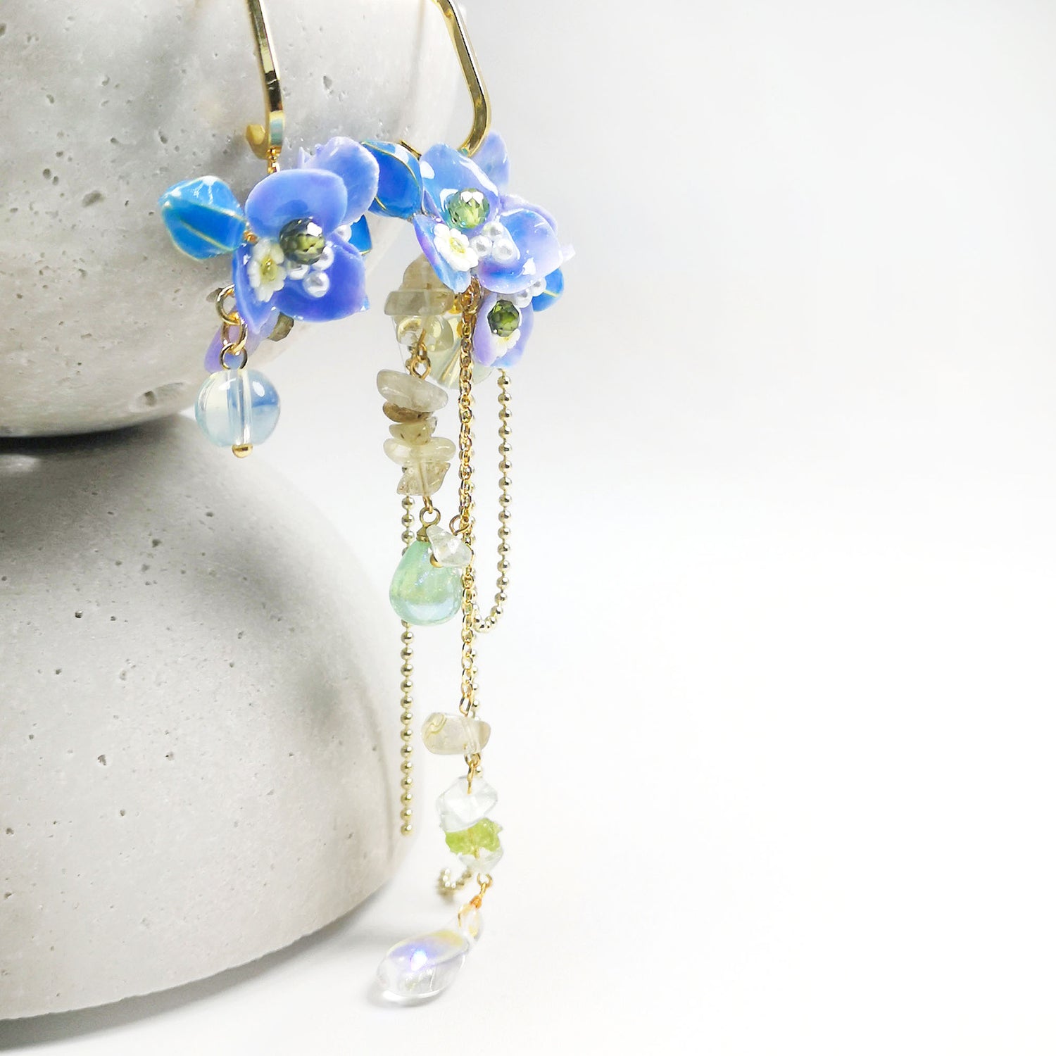 Gold-plated dangle earrings featuring real blue hydrangea flowers, hand-painted resin petals, and cascading semi-precious stone beads.