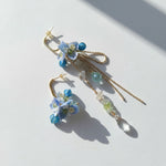 Pair of floral earrings with blue and green beads on a light background