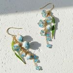 Floral earrings with blue and white flowers on a light background