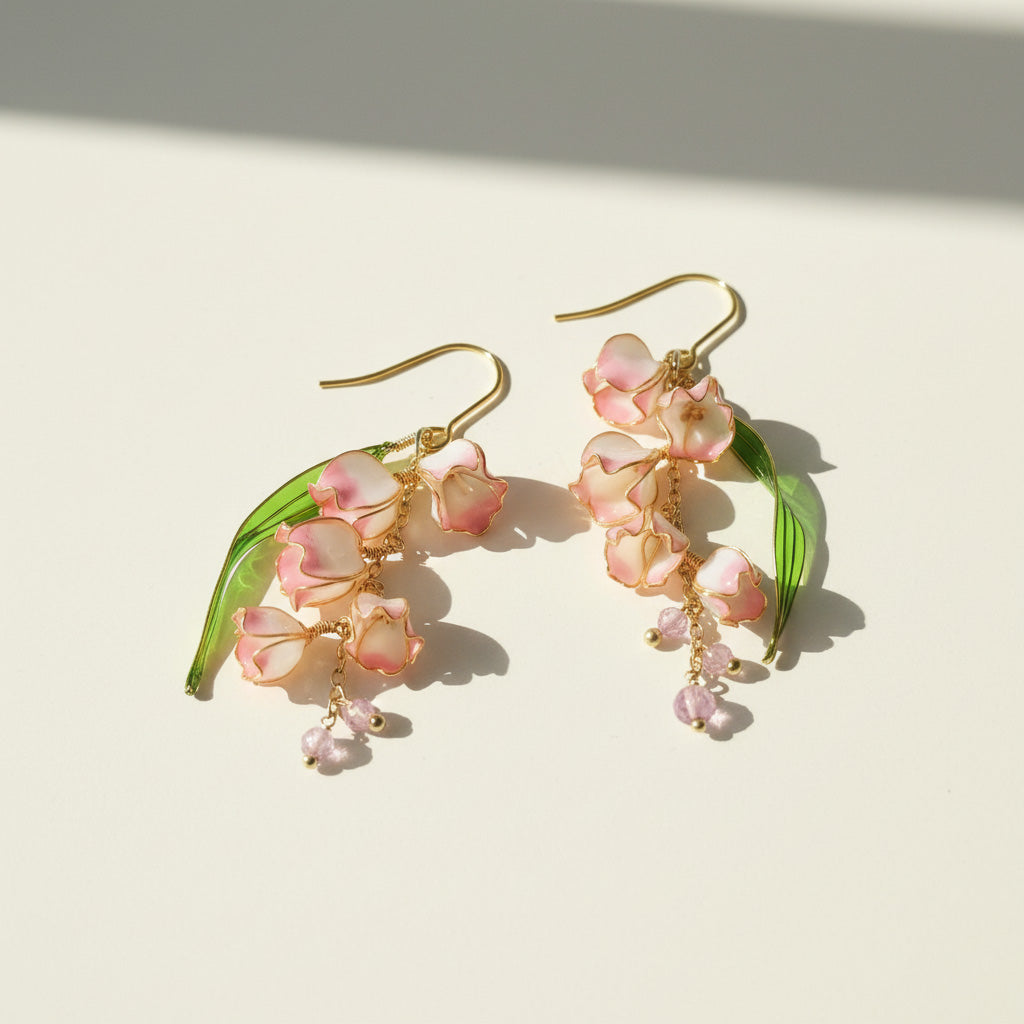 Floral earrings with pink flowers and green leaves on a light background