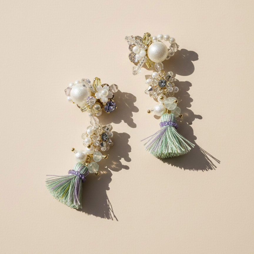 Pair of decorative earrings with pearls and tassels on a beige background