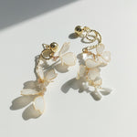 Gold and white floral earrings on a light background