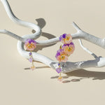 Floral earrings on a white branch against a beige background