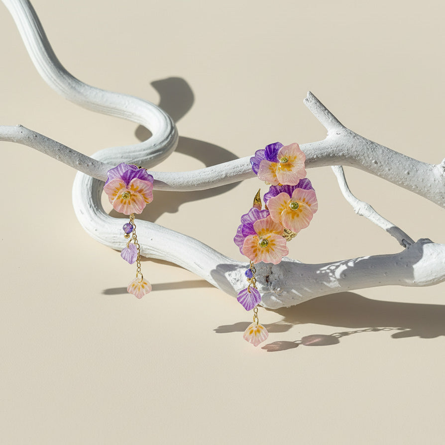 Floral earrings on a white branch against a beige background