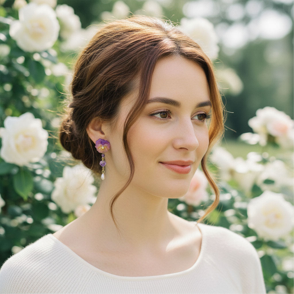 Woman with styled hair and earrings standing in a garden with white flowers