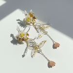 Decorative earrings with floral and butterfly designs on a light background