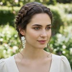 Model wearing porcelain flower and pearl drop earrings outdoors.