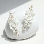 White floral earrings on a white stone surface