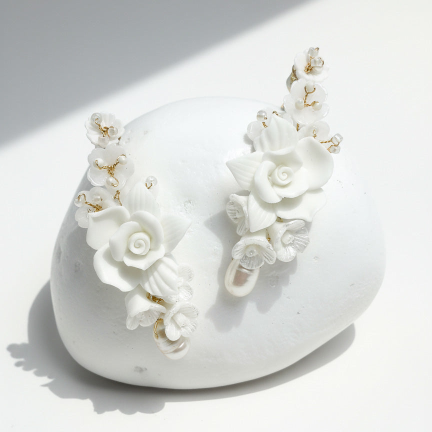 White floral earrings on a white stone surface