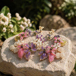 Bracelet with pink and purple floral beads on a stone surface with flowers in the background