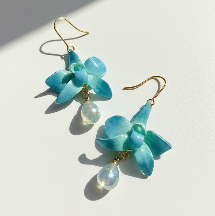Pair of blue flower-shaped earrings with gold hooks on a light background