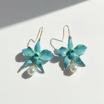 Teal flower-shaped earrings with pearl drops on a white background