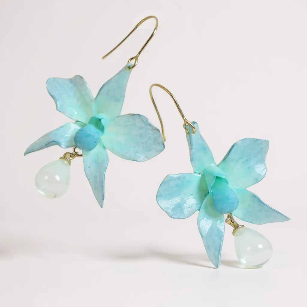 Pair of light blue orchid-shaped earrings on a white background