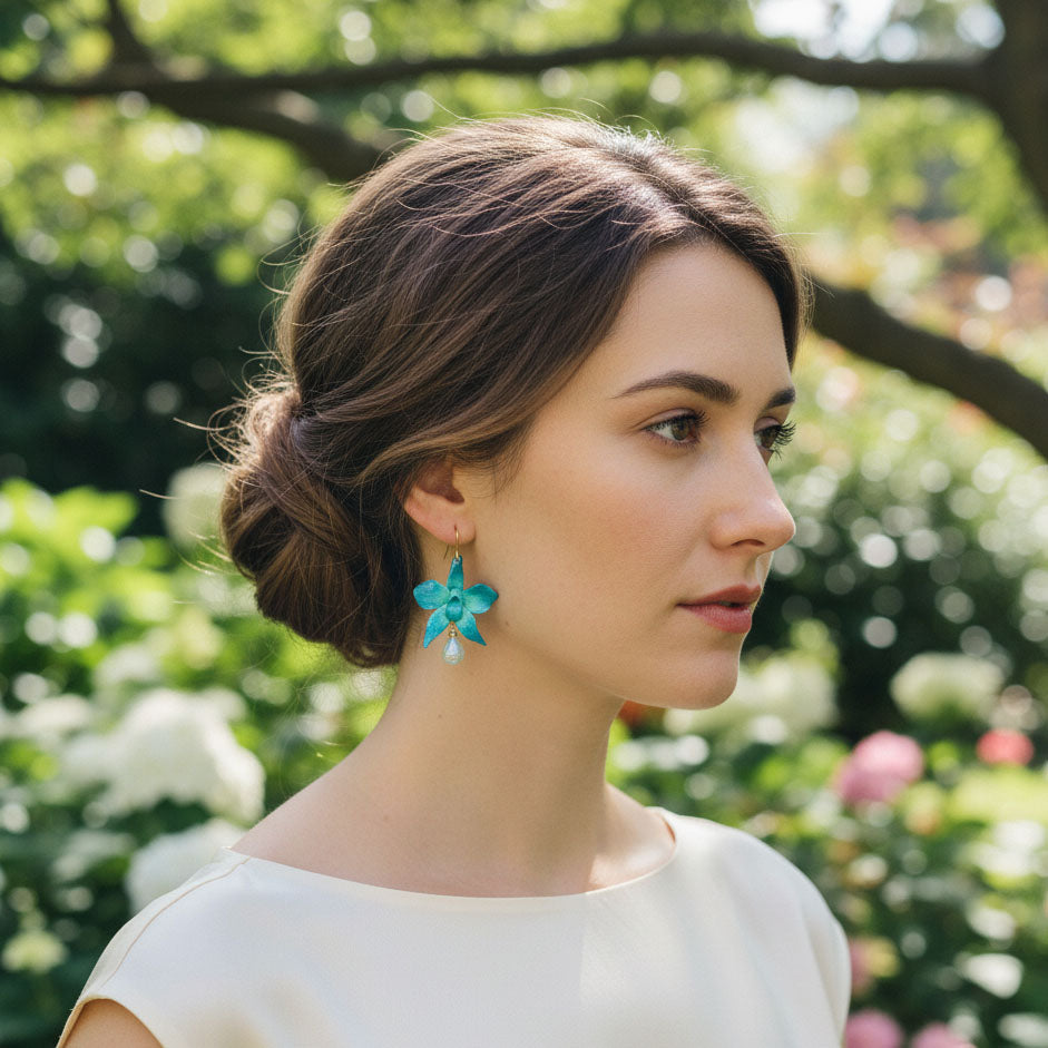 Woman wearing turquoise earrings with a blurred garden background