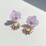 Pair of earrings with purple floral elements on a light background