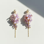 Pair of floral earrings with gold chains on a light background