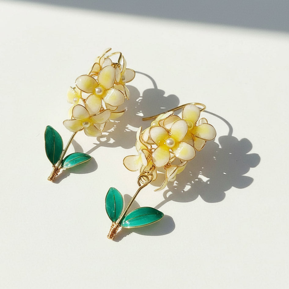 Floral earrings with yellow flowers and green leaves on a white background