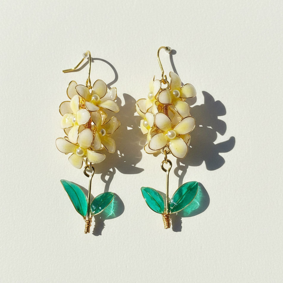 Floral earrings with yellow flowers and green leaves on a light background