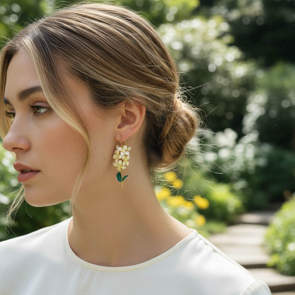 Woman wearing floral earrings outdoors with greenery in the background