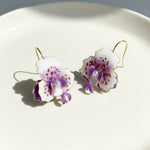 Orchid-shaped earrings on a white plate with a light background